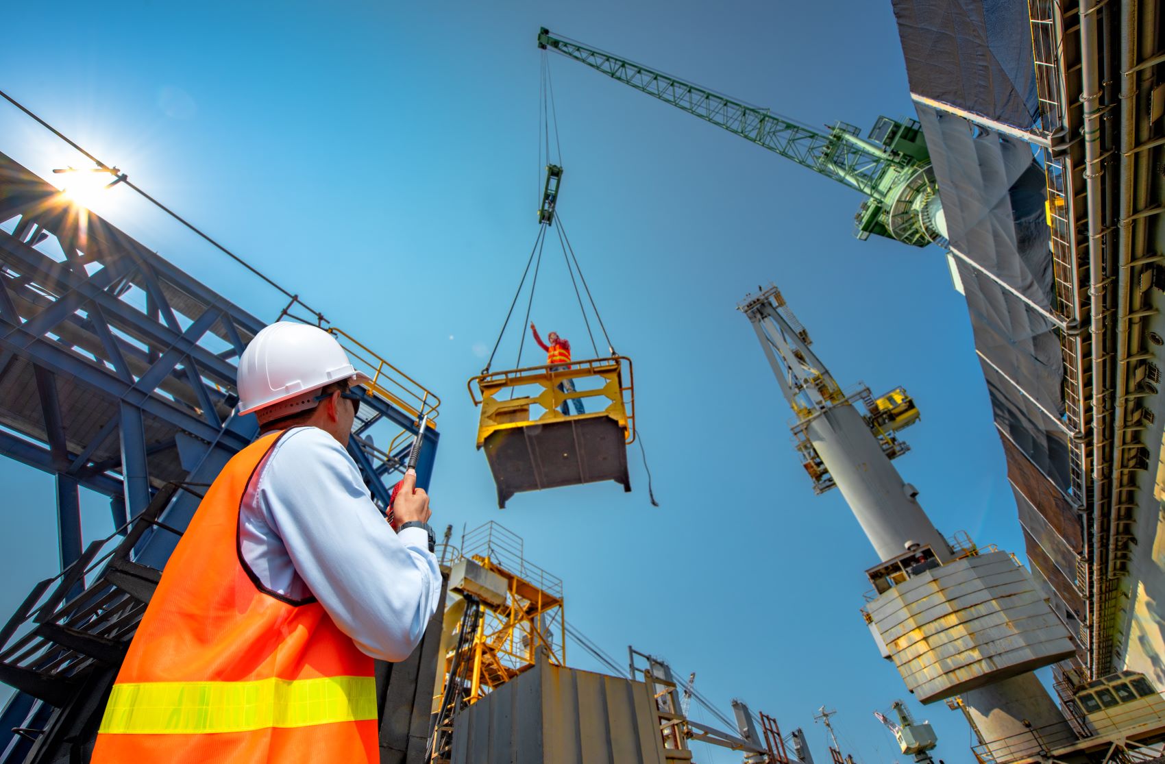 person in construction using long-range two-way radio to communicate with employee at work