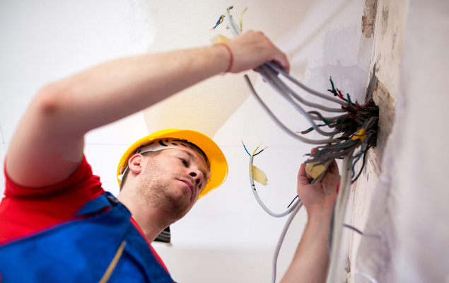 man working on wires coming through a wall